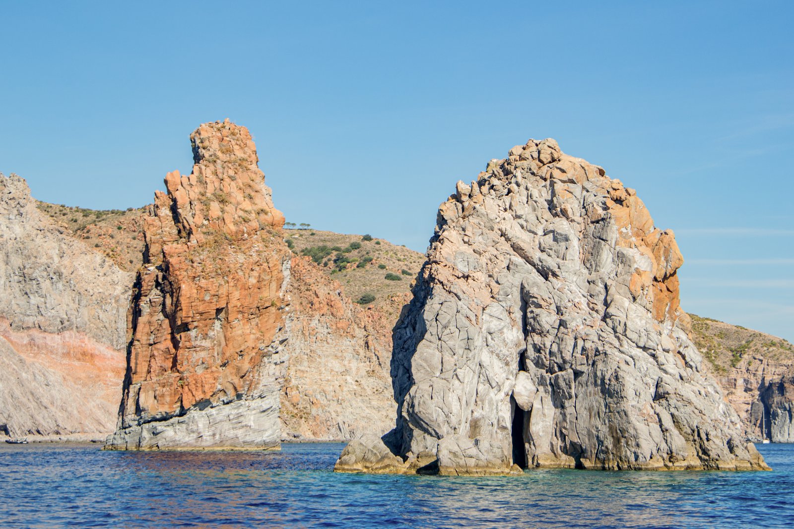 Sunlit Aeolian sea stacks rising from clear blue water