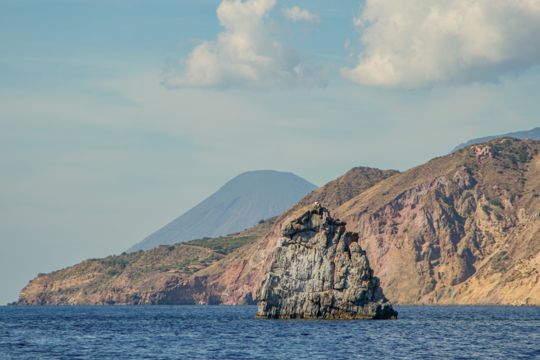 A solitary rock formation beside the rugged coastline